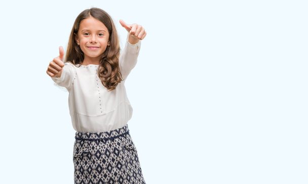 Brunette-Spaanse meisje houdende goedkeuring van het doen van positief gebaar met hand, thumbs glimlachen en blij voor succes. Kijkend naar de camera, winnaar gebaar. - Foto, afbeelding