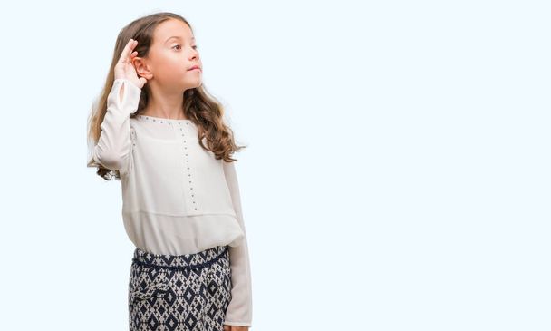 Menina hispânica morena sorrindo com a mão sobre o ouvido ouvindo uma audição para boatos ou fofocas. Conceito de surdez
. - Foto, Imagem