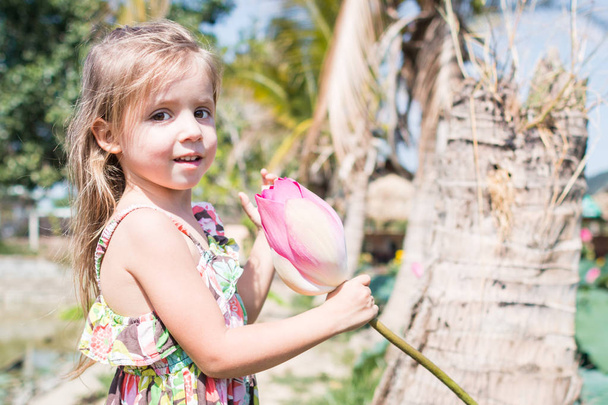 Esta hermosa flor de nenúfar o loto. La niña sostiene en sus manos una flor y sonríe
. - Foto, Imagen