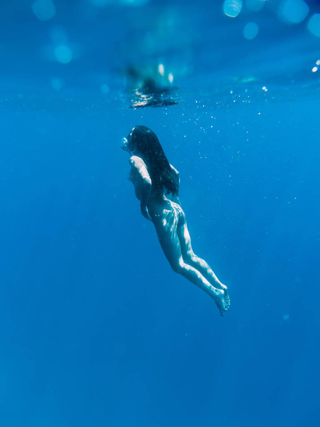 Gyönyörű meztelen nő lebeg a tenger, a kék óceán víz alatti - Fotó, kép