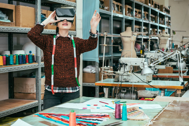 Asian woman wearing wearing VR headset device to see the blueprint of the new designed clothes. - Photo, image