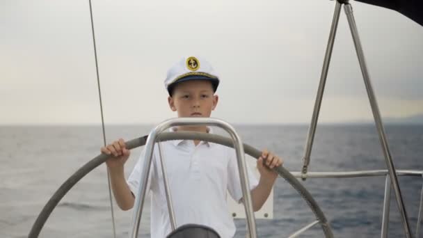 Litle dzieci skipper w kontroli steru jachtu podczas wyścigu. - Materiał filmowy, wideo
