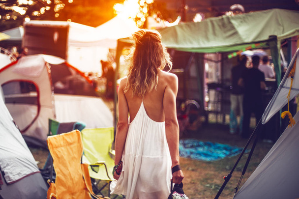 Beautiful young woman walking on festival camping tents for sunset dancig party - Photo, Image