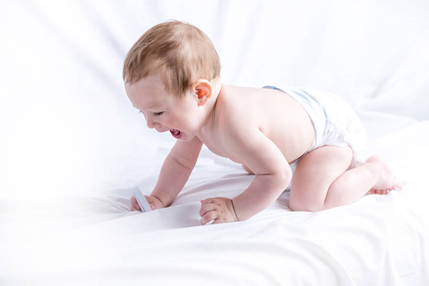 Mignon bébé aux yeux bleus 6-9 mois souriant et jouant sur fond blanc. Les émotions des enfants. Propreté et soins pour bébés
 - Photo, image