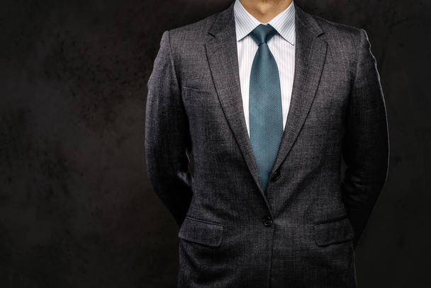 Cropped portrait of a successful businessman dressed in an elegant formal suit. Isolated on a dark background. - Photo, Image