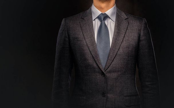 Retrato recortado de un exitoso hombre de negocios vestido con un elegante traje formal. Aislado sobre un fondo oscuro
. - Foto, Imagen