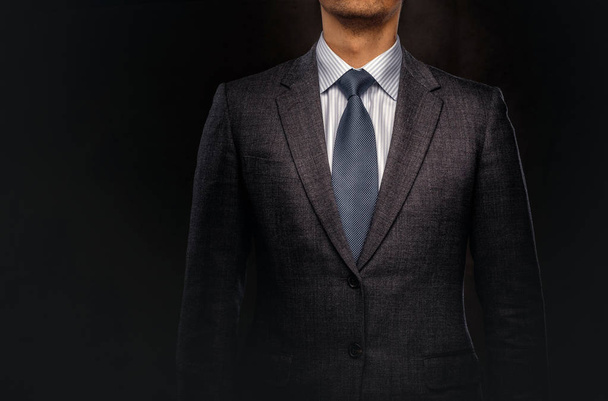 Retrato recortado de un exitoso hombre de negocios vestido con un elegante traje formal. Aislado sobre un fondo oscuro
. - Foto, Imagen