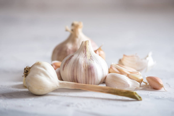 Group of garlic cloves scattered on a table on a white background. An important ingredient in different cuisines of the world. A healthy product. - Foto, afbeelding