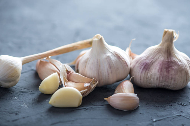 Group of garlic cloves scattered on a table on a white background. An important ingredient in different cuisines of the world. A healthy product. - Fotografie, Obrázek