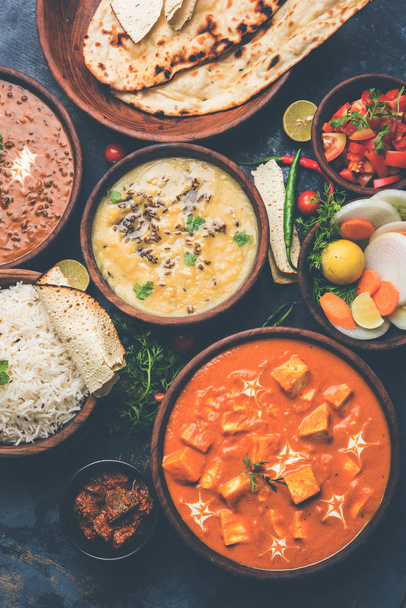Geassorteerde Indiaas eten voor lunch of diner, rijst, linzen, paneer, dal makhani, naan, chutney, kruiden over humeurig achtergrond. selectieve aandacht - Foto, afbeelding