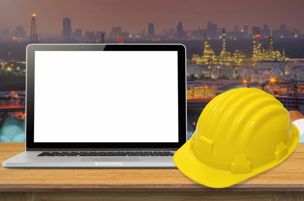 Sarı kask ve sanayi arka plan, ekran üzerinde boş masa üstünde laptop. - Fotoğraf, Görsel