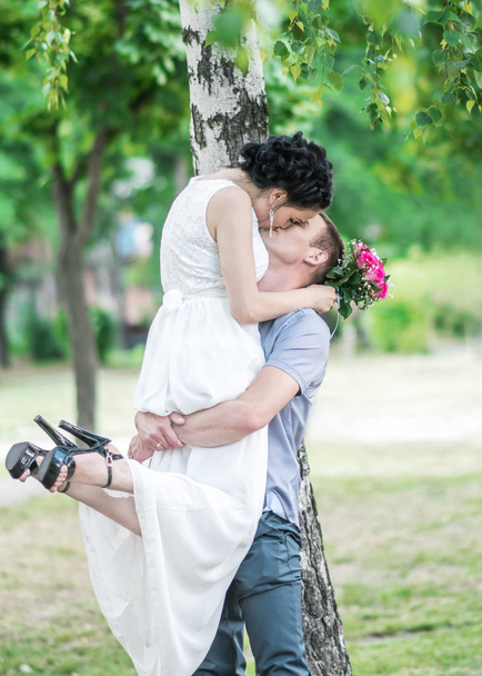 Портрет красивой молодой пары невесты и поцелуя жениха в летнем парке. Муж вырастил жену. Пара влюблённых. Счастливая семья
 - Фото, изображение