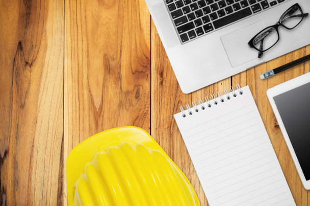 Top view scrivania ingegnere con casco giallo, smart phone, tazza di caffè, nota di carta, occhiali e attrezzature per ufficio
. - Foto, immagini