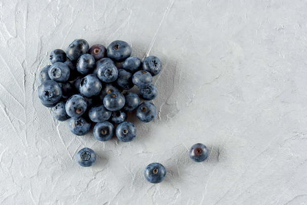 Blueberry on a gray cement background. Ripe and juicy fresh blueberry close-up. A bunch of berries close-up. - Zdjęcie, obraz