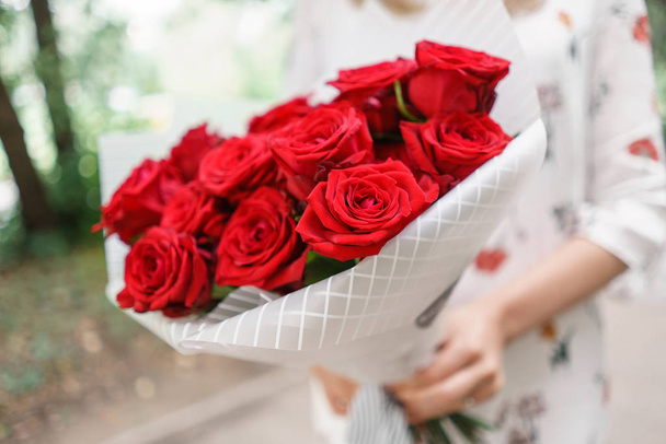 Beautiful bouquet. Young girl holding a flower arrangement with red roses. The concept of a flower shop. Content for the catalog - Foto, Bild