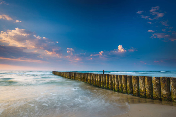 Pôr do sol na praia com quebra-mar, exposição de longa data
 - Foto, Imagem