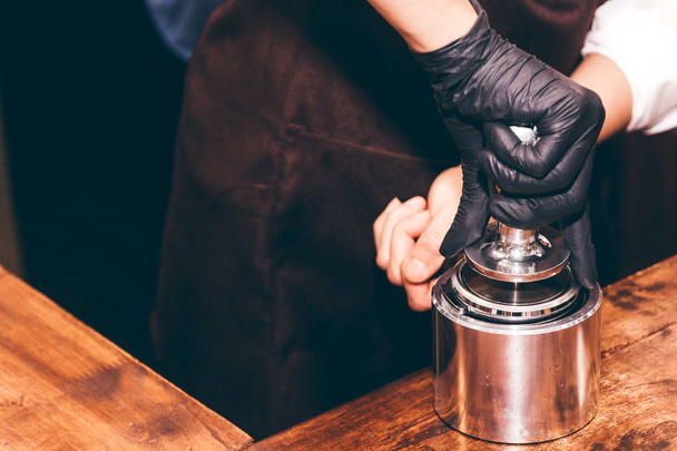 Barista using tamper to makes coffees in coffee bar - 写真・画像