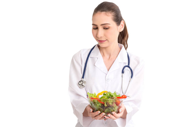 Ärztin hält einen Teller mit frischem Gemüsesalat auf weißem Hintergrund - Foto, Bild