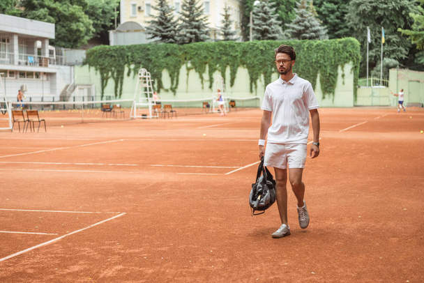 old-fashioned tennis player walking with bag after training on tennis court  - Photo, Image