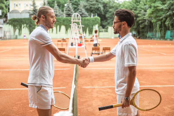 木製ラケット裁判所での試合後に握手と昔ながらのテニス選手 - 写真・画像