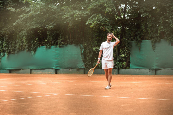 handsome tennis player with racket standing on tennis court - Photo, Image