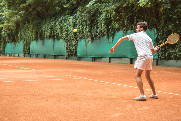 старомодный спортсмен играет в теннис с ракеткой и мячом на теннисном корте
 - Фото, изображение