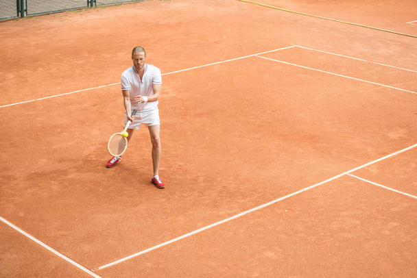 staromódní tenista školení s dřevěnou raketu a míček na hnědé soudu - Fotografie, Obrázek