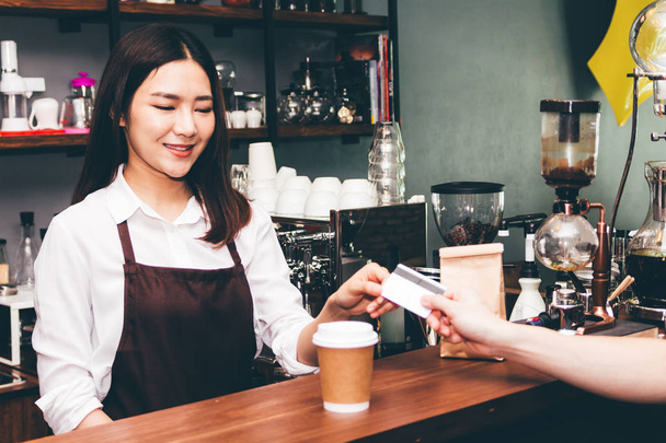 Vrouwelijke barista nemen een creditcard van de klant in de coffeeshop - Foto, afbeelding