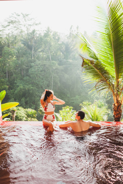 Jeune couple relaxant dans une piscine privée de luxe à débordement avec vue imprenable sur la jungle d'en haut à Bali
 - Photo, image