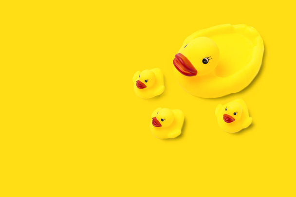 Sarı renkli plastik oyuncak anne ördek ve sarı arka planda küçük ördek yavruları. Anne bakımı ve çocuk sevgisi kavramı. Düz yatış, üst görünüm. - Fotoğraf, Görsel