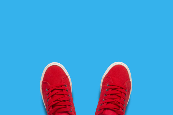 Червоні кросівки на синьому фоні. Стиль мінімалізму. Плоский прошарок, вид зверху
. - Фото, зображення