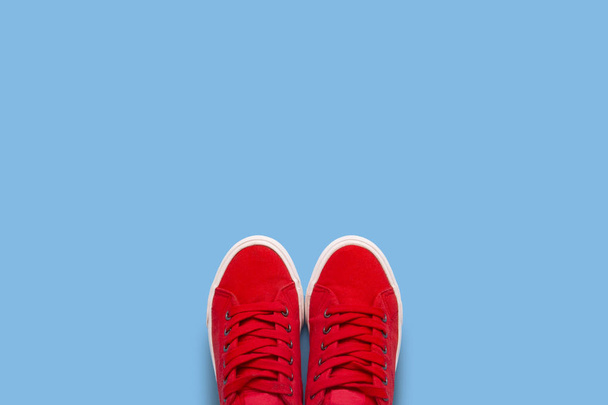 Red sneakers on a blue background. Minimalism style. Flat lay, top view. - Foto, Imagem