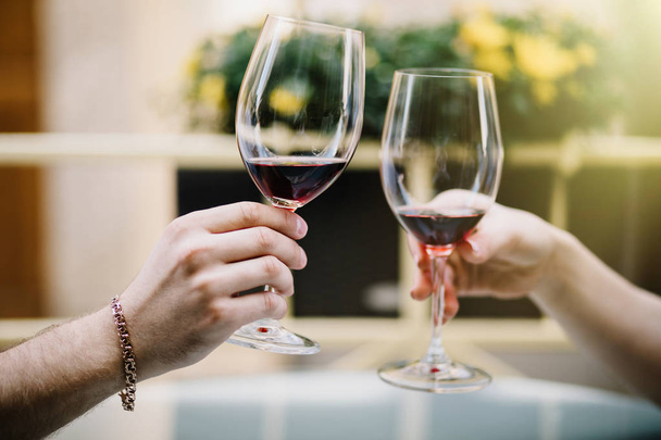 Alla salute. Giovane coppia amorevole seduta vicino a vicenda sorridente e brindare con due bicchieri di vino rosso
. - Foto, immagini