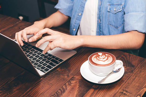 Женщина пьет кофе и работает за ноутбуком в кафе
 - Фото, изображение