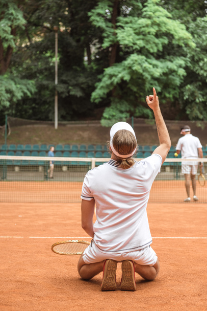 staromódní tenista ukázal nahoru a na kolenou po výhře na hřišti - Fotografie, Obrázek