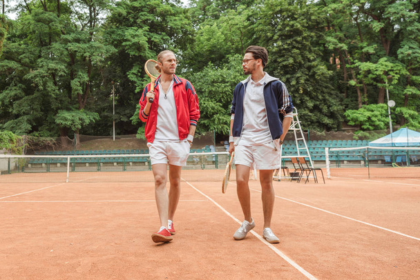 retro stijl vrienden met houten rackets lopen op Tennisbaan - Foto, afbeelding
