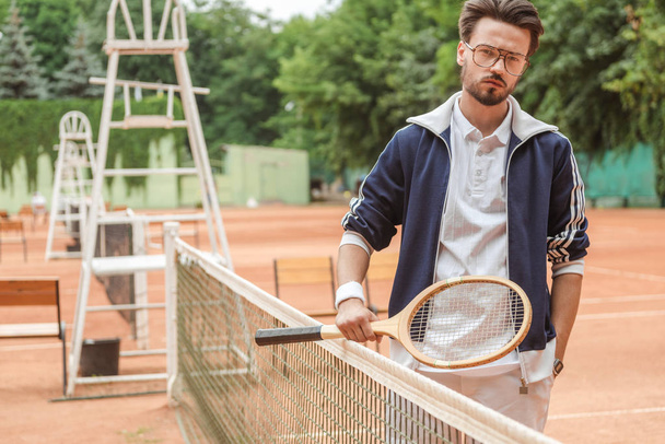 όμορφος ρετρό στυλ παίκτης του τένις με ξύλινη ρακέτα στο γήπεδο - Φωτογραφία, εικόνα