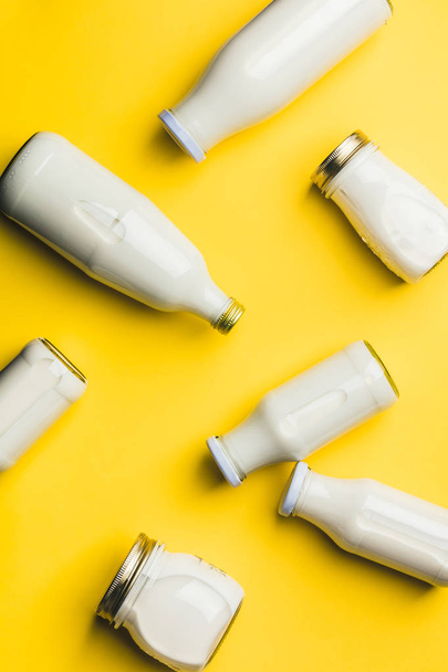 Various bottles of milk on yellow background - Valokuva, kuva