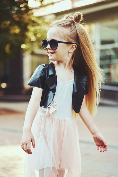 Lifestyle portrait of stylish little girl teenager. Beautiful child, wearing black jacket, pink skirt. Beautiful long hair. - Fotoğraf, Görsel