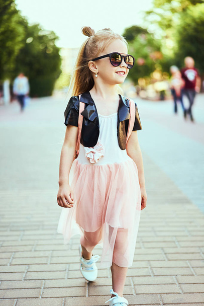 Lifestyle portrait of stylish little girl teenager. Beautiful child, wearing black jacket, pink skirt. Beautiful long hair. - Фото, зображення