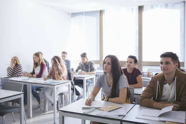 Group of a high school students having a class at modern classroom. - Фото, изображение