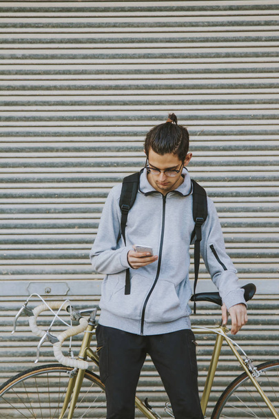 young fashion with bike and mobile phone in the city - Photo, Image