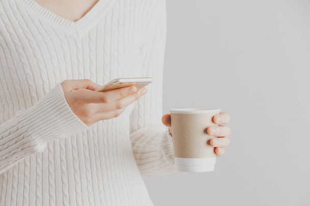 Měkké zaostření mladá dívka ruce pomocí smartphone a držet šálek kávy. Kopírovat prostoru. Komunikační koncept přestávka na kávu. Nápis - Fotografie, Obrázek