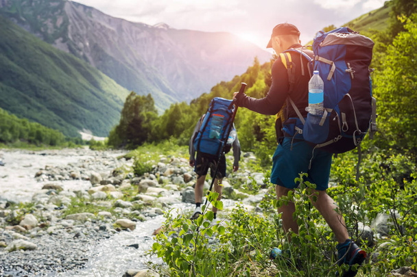 Tourists with hiking backpacks on beautiful mountain landscape background. Climbers hike to mounts. Group of hikers walking in mountains - Photo, image