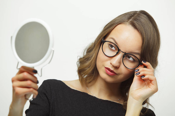 Stylish woman trying on spectacles with mirror in hands on white isolated background. - Fotó, kép