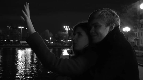 Egy szerelmes pár áll ellen a waterfront éjszakai város fényei. Csodálatos esküvő házaspár folyó közelében, éjjel, fekete-fehér - Fotó, kép