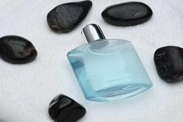 szampon butelka czarny kamienie na biały ręcznik - Zdjęcie, obraz