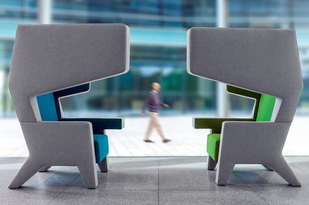 Два сучасних порожніх крісла в інтер'єрі залу очікування з ходячою розмитою людиною на задньому плані
 - Фото, зображення