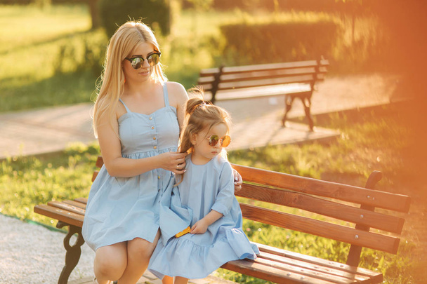 Maminka a jeho malá dcera sedí na lavičce v parku - Fotografie, Obrázek