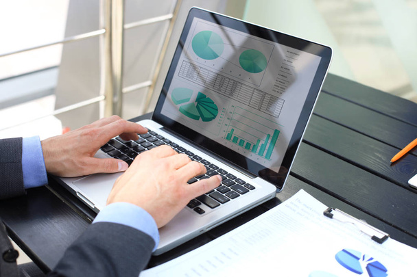 Persona de negocios que analiza las estadísticas financieras que se muestran en la pantalla del ordenador portátil
 - Foto, imagen